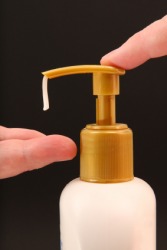Someone dispensing lotion into their hand. Someone dispensing lotion into their hand.