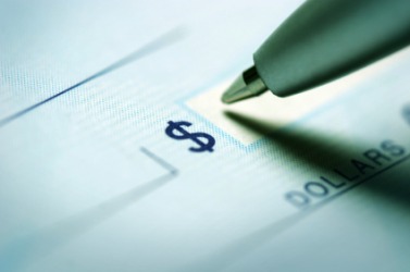 A pen getting ready to write next to a dollar sign. A pen getting ready to write next to a dollar sign.