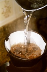 Hot water being poured through coffee in a filter. Hot water being poured through coffee in a filter.