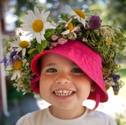 A child with a garland of flowers on her hat. A child with a garland of flowers on her hat.