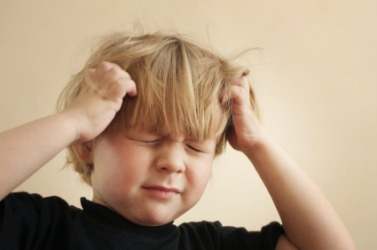 A little boy holding his head. A little boy holding his head.