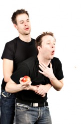 A man administers the Heimlich maneuver to another. A man administers the Heimlich maneuver to another.