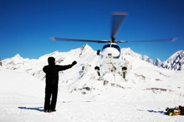 A heli-skiier waves to the helicopter. A heli-skiier waves to the helicopter.