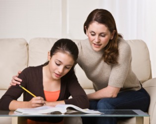 A woman helps her daughter with her homework. A woman helps her daughter with her homework.