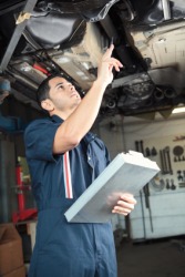 A mechanic inspects an automobile. A mechanic inspects an automobile.