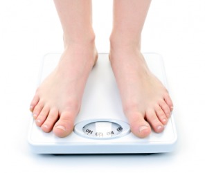 A woman weighs herself on a bathroom scale. A woman weighs herself on a bathroom scale.