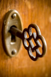 An old fashioned key inserted in a keyhole. An old fashioned key inserted in a keyhole.