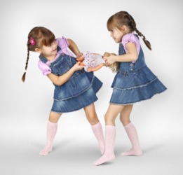 Two little girls quarrel over a doll. Two little girls quarrel over a doll.