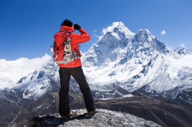 A hiker views a snow covered mountain range. A hiker views a snow covered mountain range.
