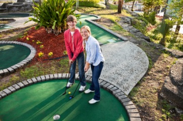 Teenagers playing miniature golf. Teenagers playing miniature golf.