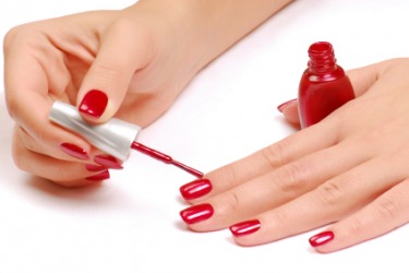 A woman applies bright red nail polish. A woman applies bright red nail polish.