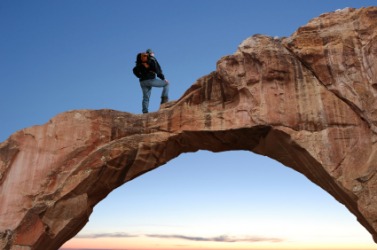A man stands on a natural bridge. A man stands on a natural bridge.