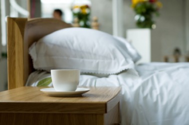 A cup sits on this nightstand. A cup sits on this nightstand.