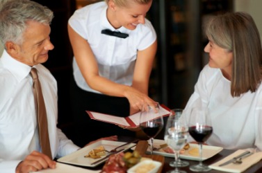 A waiter assists a couple with their restaurant order. A waiter assists a couple with their restaurant order.