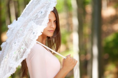 A woman poses with a lacey parasol. A woman poses with a lacey parasol.