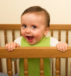 A cute baby holding the rail of his crib. A cute baby holding the rail of his crib.