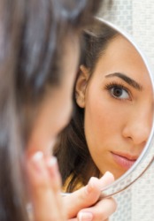 A woman looks at her reflection in a mirror. A woman looks at her reflection in a mirror.