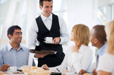 A waiter brings coffee to his customers. A waiter brings coffee to his customers.