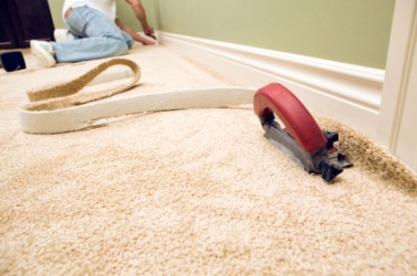 A man installing wall-to-wall carpeting. A man installing wall-to-wall carpeting.