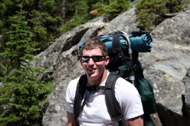 A hiker with a bedroll on top of his backpack. A hiker with a bedroll on top of his backpack.