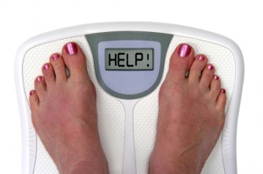 A woman weighs herself on her bathroom scales. A woman weighs herself on her bathroom scales.