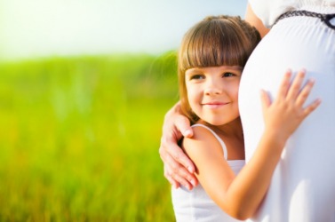A little girl hugs her mommys baby bump. A little girl hugs her mommys baby bump.