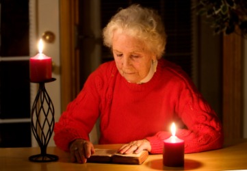 A woman reads by candlelight during a blackout. A woman reads by candlelight during a blackout.