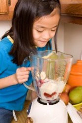 A girl blending ingredients to make a smoothie. A girl blending ingredients to make a smoothie.