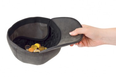 A hand holding out a cap to beg. A hand holding out a cap to beg.