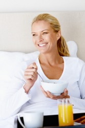 A woman enjoys breakfast in bed. A woman enjoys breakfast in bed.