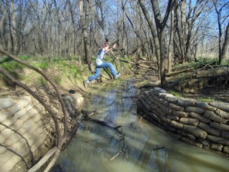 A boy leaps across a stream. A boy leaps across a stream.