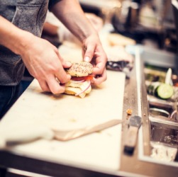 A person creating a made to order sandwich. A person creating a made to order sandwich.