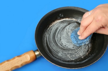 A person scours a dirty pan. A person scours a dirty pan.
