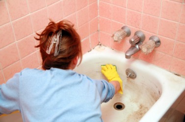 A woman scrubs her bathtub. A woman scrubs her bathtub.